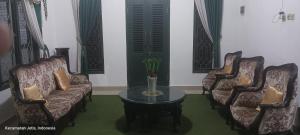 a living room with couches and a table with a vase at Adiyantum Homestay in Jetis
