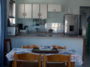 a kitchen with a table and chairs and a refrigerator at Sea Urchin in Gordonʼs Bay