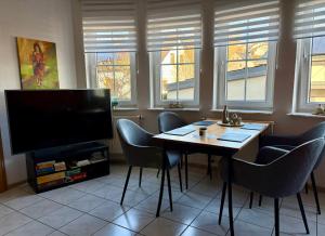 a living room with a table with chairs and a television at Ferienwohnung Kaspers in Schalkenmehren +13 photos