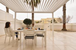 a woman sitting at a white table in a patio at LifeStyle Boutique Apartment in Monopoli