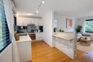 a kitchen and living room with a stone fireplace at Coastal Stay in Cronulla