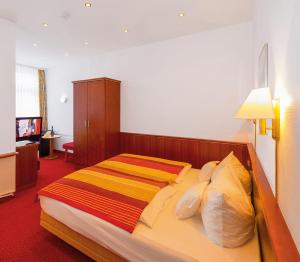 a bedroom with a bed with a striped blanket on it at Inselhotel Ihnken in Norderney
