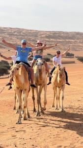 Eine Gruppe von Menschen, die in der Wüste auf Pferden reiten in der Unterkunft Sand Camp Oman in Badīyah