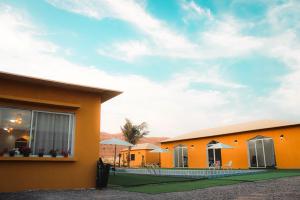 Ein orangefarbenes Haus mit einer Palme im Hintergrund in der Unterkunft Sand Camp Oman in Badīyah