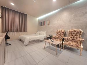 a hotel room with a bed and two chairs and a table at Hotel Terry's in Suwŏn-yŏk
