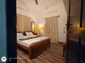 a bedroom with a bed with white sheets and curtains at Sandy Steps in Varkala