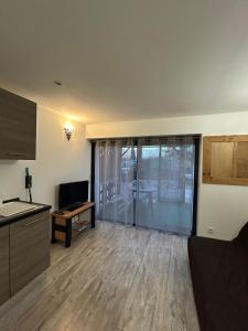 a living room with a kitchen and a living room with a television at Studio au calme les hirondelles in Les Mées