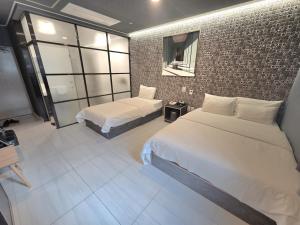 a bedroom with two beds and a brick wall at Hotel Terry's in Suwŏn-yŏk
