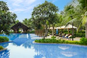 a pool at a resort with chairs and umbrellas at Costamigo Phan Thiet, BW Premier Collection in Phan Thiet