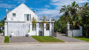 a white house with a gate and grass at Huis Marais in Herolds Bay