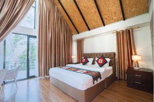 a bedroom with a bed and a large window at Lao Asia Resort Luangprabang in Luang Prabang