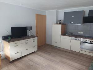 a kitchen with white cabinets and a flat screen tv at Haus Holzer in Dorfgastein +15 photos