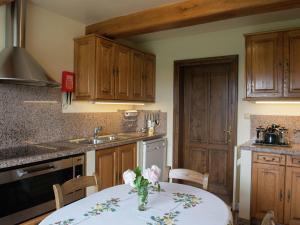 een keuken met een tafel met een vaas met bloemen erop bij Spacious and well cared for house with a panoramic view sauna and a summer pool in Habiemont