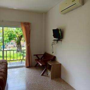a living room with a couch and a tv on the wall at Banmairimfungnamkohchang in Ban Dan Kao