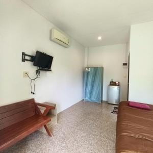 a living room with a bench and a tv on the wall at Banmairimfungnamkohchang in Ban Dan Kao +12 photos
