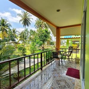 a balcony with a table and chairs and palm trees at Banmairimfungnamkohchang in Ban Dan Kao