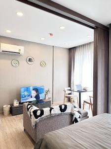 a bedroom with a couch and a tv in a room at Muay Thai Apartment - Ratchada in Bangkok