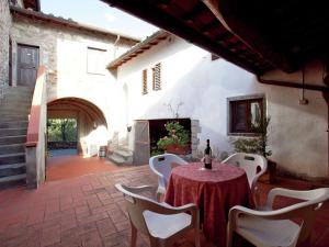 una mesa con sillas blancas y una botella de vino en Serene Apartment with Garden Pool Terrace Deckchairs en Lucolena in Chianti