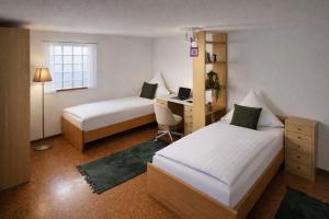a bedroom with two beds and a desk with a laptop at SK Ferienapartments Kappelrodeck in Kappelrodeck
