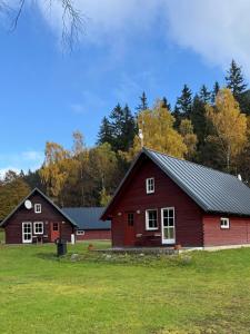 a red barn and a red house on a field at Chalets & Apartments - Base Camp Medvědín in Špindlerův Mlýn