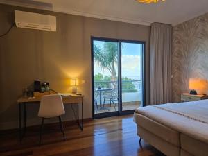a hotel room with a bed and a desk and a balcony at Casa do Mundo Madeira in Gaula
