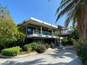 a large building with a balcony and a palm tree at Tamnan Resort Pattaya in Ban Nong Chaeng