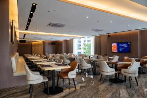 a dining room with tables and chairs and a screen at Asteria Melaka by Attic Suite in Malacca