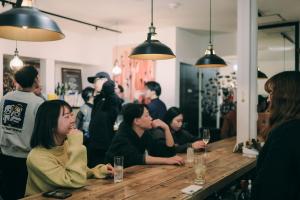 a group of people sitting at a table in a restaurant at Public Guest House in Karuizawa