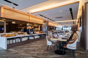 a restaurant with a long bar with white chairs at Asteria Melaka by Attic Suite in Malacca