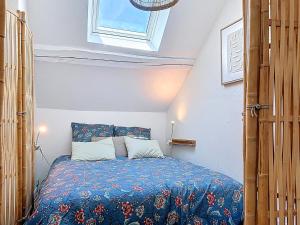 a bedroom with a bed with a blue comforter and a window at Le Balcon des Rois in Dourdan