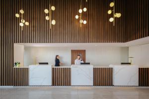 two people standing at a counter in a lobby at NissiBlu Beach Resort in Ayia Napa +48 photos