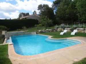 a swimming pool in a yard with two chairs in it at Charming Holiday Home in Tourtour, Provence with Garden in Tourtour