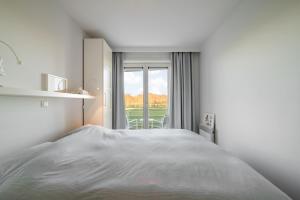 a white bedroom with a bed and a window at Port Albert by BLOSS in Nieuwpoort