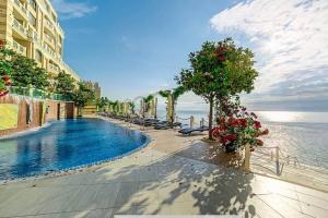 a swimming pool next to a building and the ocean at Seaside Sunset - free parking in Golden Sands