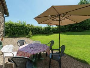 Quaint Cottage In Jevign with Terrace في Lierneux: طاولة وكراسي مع مظلة في الفناء