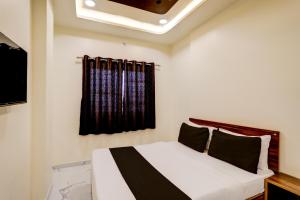 a bedroom with a white bed with a window at Hotel O highway blues in Nagpur