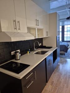 a kitchen with white cabinets and a sink and a stove at Pratt St Brand New Studio Loft Elevator Building in Hartford