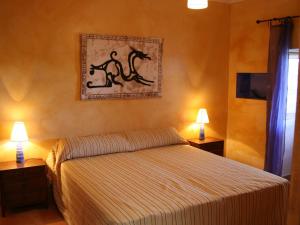 a bedroom with a bed with two lamps and a painting on the wall at Holiday Home in St Josep de sa Talaia with Pool in Sant Josep de sa Talaia +20 photos