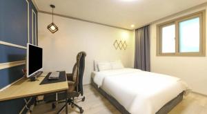 a bedroom with a bed and a desk with a computer at 위드유 호텔 광주역 in Kwangju-yŏk