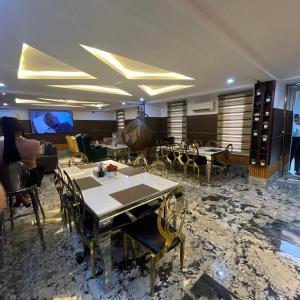 a dining room with tables and chairs and a tv at Dephantom Continental Hotel in Lagos
