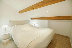 a white bedroom with a white bed and wooden ceilings at Saint Tropez High standing 3 in Saint-Tropez