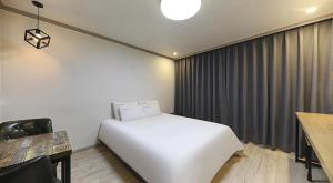 a bedroom with a white bed and a table and chair at 위드유 호텔 광주역 in Kwangju-yŏk