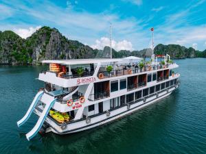 a boat in the water with mountains in the background at Cat Ba Flora Hotel in Cat Ba