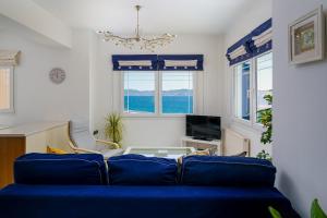 a living room with a blue couch and a tv at The Marina View in Lavrio +4 photos