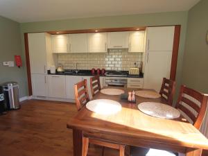 a kitchen with a wooden table with chairs and a dining room at Cottage 7 - Skye Cottage - Ukc4884 in Fort Augustus +7 photos