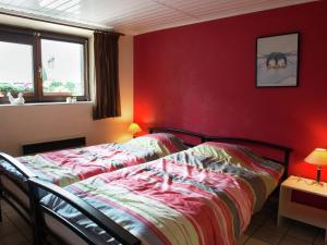 ウェームにあるChild friendly Holiday Home in Waimes with Saunaの赤い壁のベッドルーム1室(ベッド2台付)