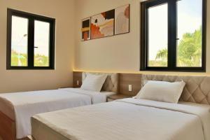 two beds in a room with two windows at Mui Da Hotel in Phan Thiet