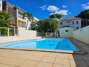 a large blue swimming pool in front of a building at NEW Appart 2 chambres avec piscine proche aeroport in Les Abymes