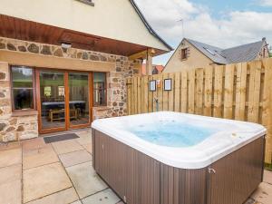 a large hot tub in a yard next to a building at Laurel Cottage - Ukc6256 in Linlithgow +3 photos