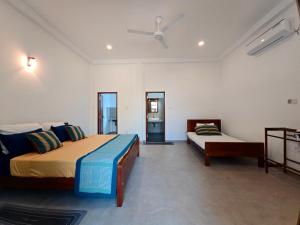 a bedroom with two beds and a ceiling fan at Olee Villa in Bentota